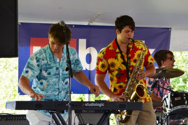 Musicians play keyboard and saxophone onstage