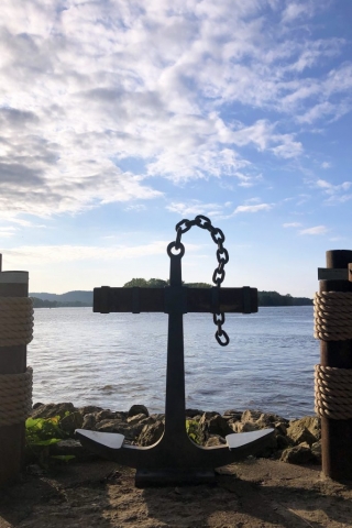 An Anchor between two wooden posts with the Mississippi River in the background