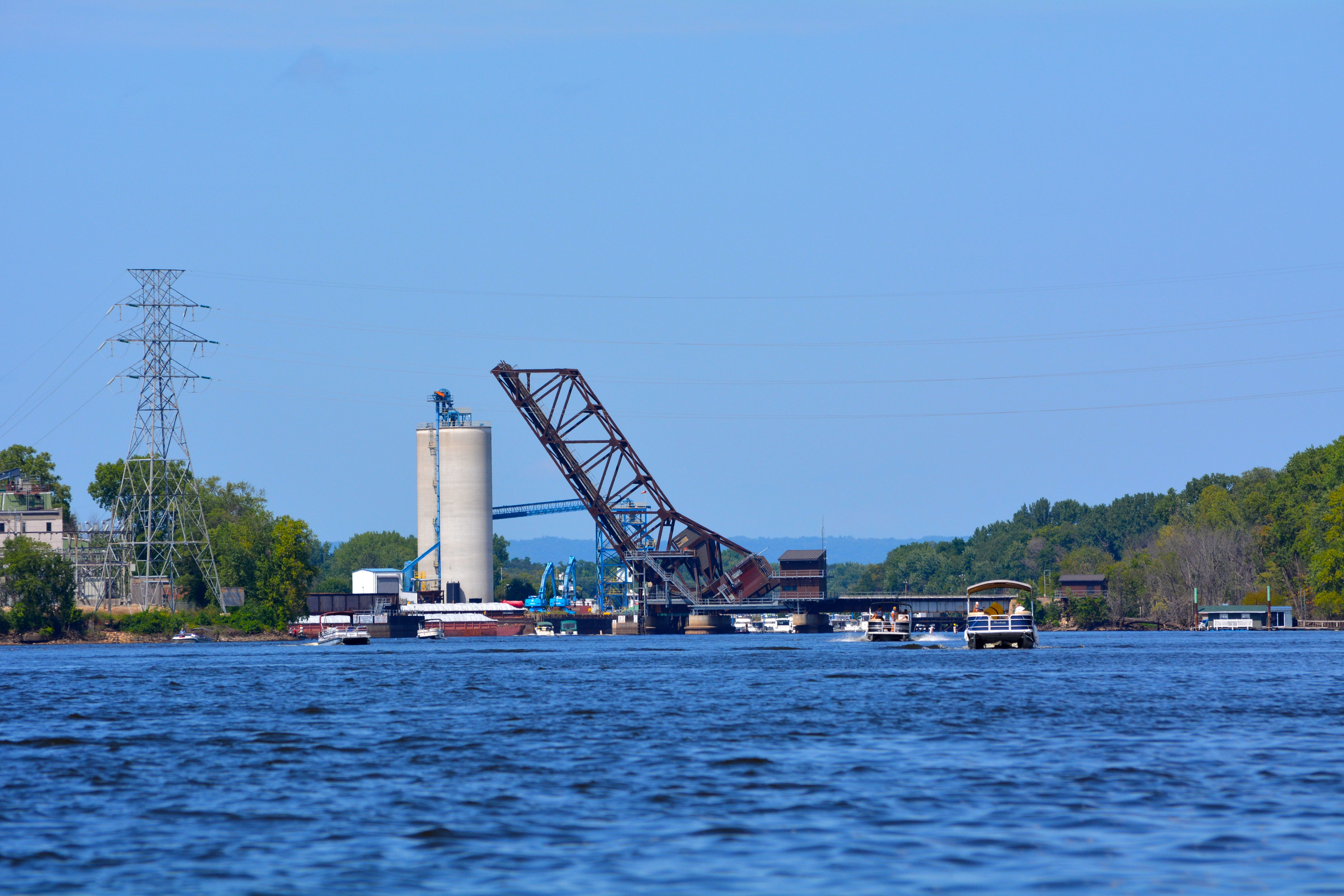 A railroad bridge rises to allow tall boats to pass underneath