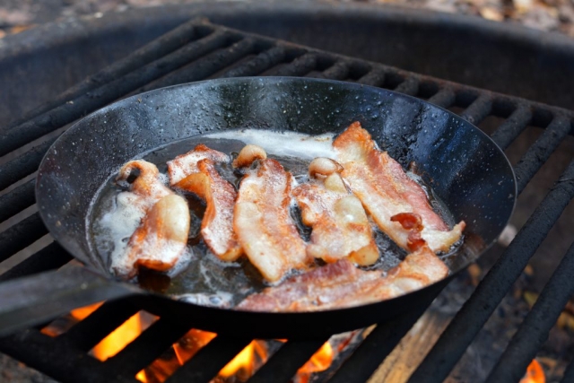 Bacon frying on an outdoor campfire