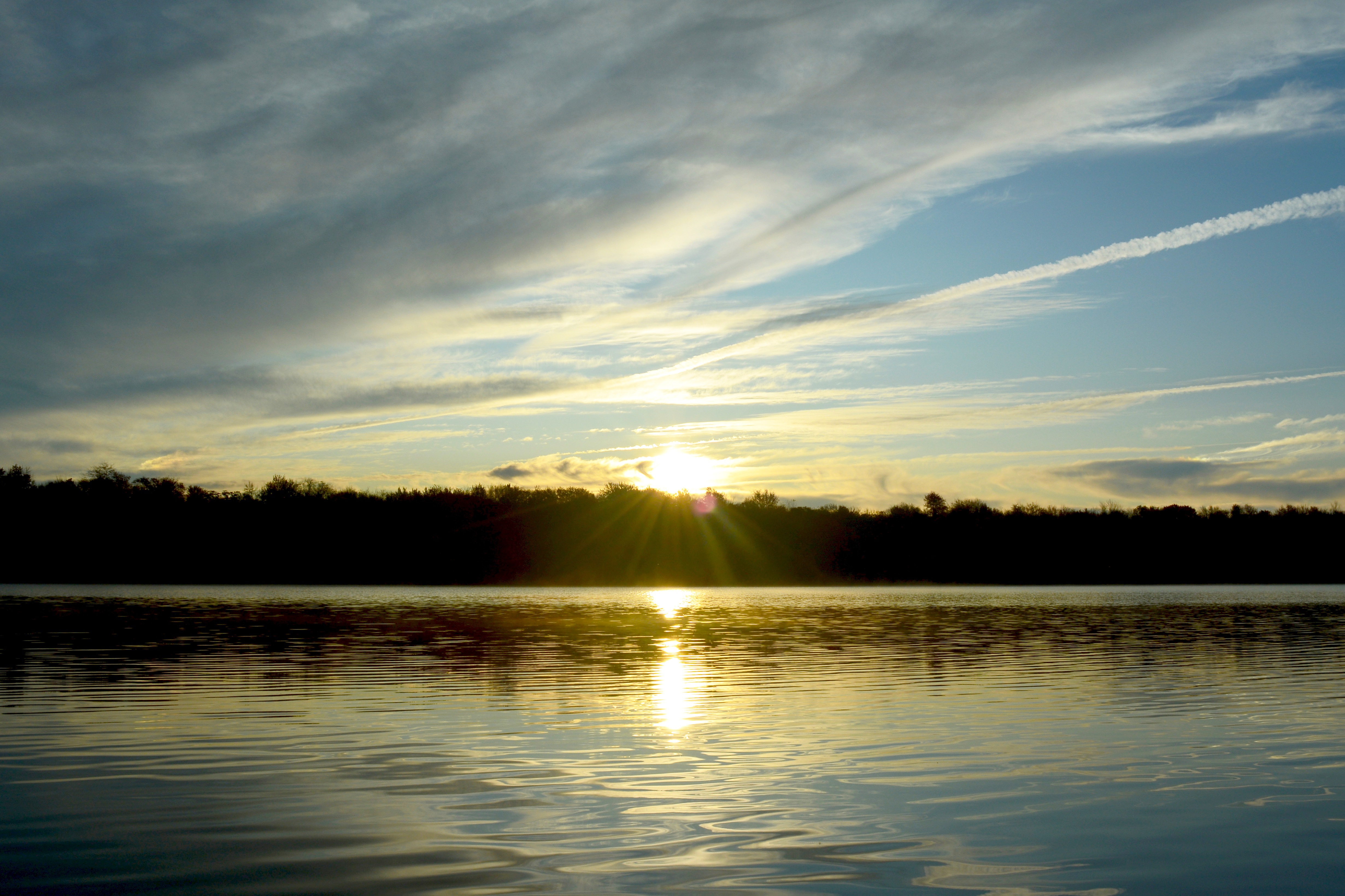 The sun rises above the trees across Tobyhanna Lake