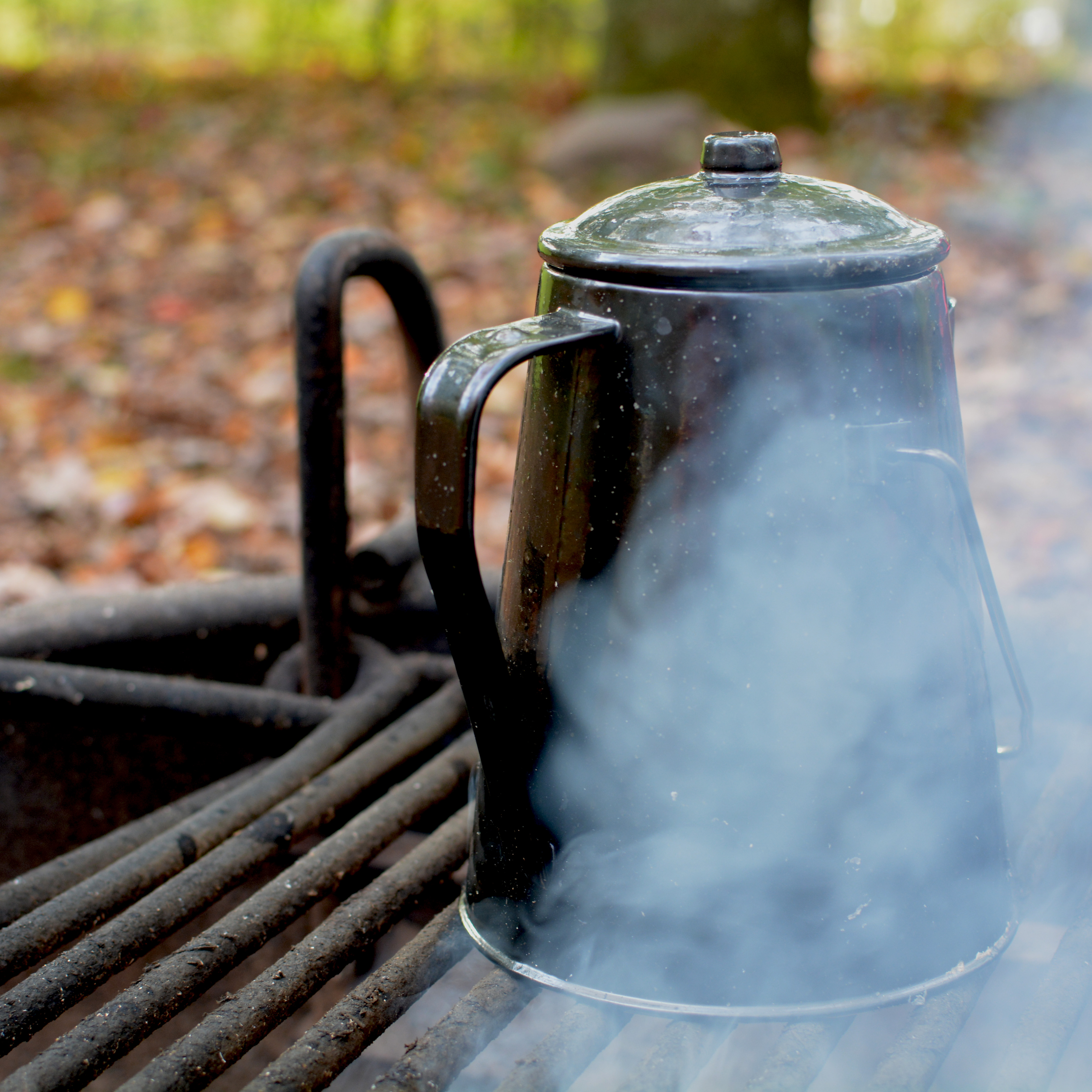 A kettle heating over an outdoor campfire