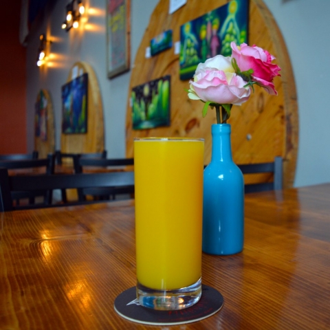 A photo of a mimosa with artwork and flowers in the background