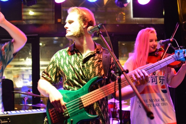 Saul plays the bass guitar; Emma plays the fiddle in the background on the right side of the image